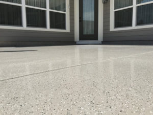 A patio outside a home with an epoxy coating that has natural stone effects.