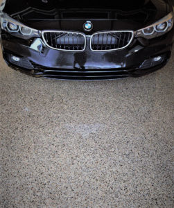 An overhead image of the front of a black BMW parked in a garage with an epoxy floor coating.