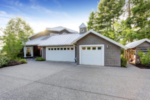 Modern luxury house exterior with curb appeal. View of garage with driveway and small porch with white columns.