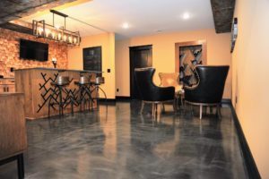 Silver metallic basement floor coating with a bar area and arm chairs