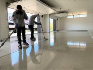 Two workers apply a floor coating in a garage